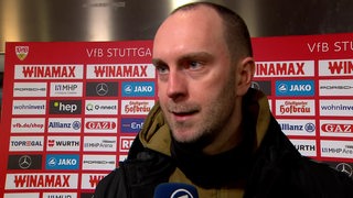 Werder-Trainer Ole Werner steht nach dem Spiel in Stuttgart vor einer roten Werbewand beim Interview.