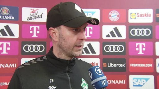Werder-Trainer Ole Werner vor einer Werbewand in München beim Interview nach dem Sieg gegen die Bayern.