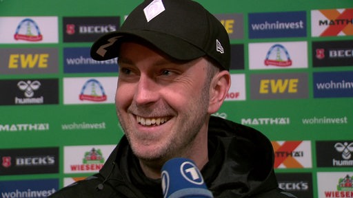 Werder-Trainer Ole Werner grinst während eines Interviews nach dem Spiel.