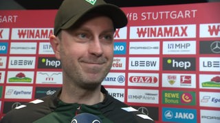 Werders Trainer Ole Werner steht nach dem Sieg in Stuttgart vor einer Werbewand beim Interview.