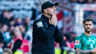 Werder-Trainer Ole Werner steht beim Spiel gegen Sankt Pauli an der Seitenlinie und legt sich nachdenklich die Hände ans Kinn.