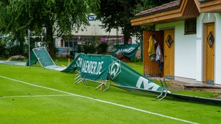 Blick auf von Sturmböen umgekippte Werbebanner am Spielfeldrand von Werders Trainingslager-Quartier in Zell am Ziller