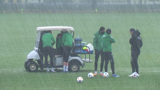 Fussballspieler von Werder Bremen während eines Hagelsturms auf einem Trainingsplatz. 