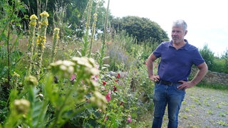 Ein Mann in Jeans in einem wild aussehenden Garten