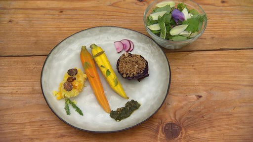 Auf dem Bremer Teller sind bunte Möhren, Kartoffelschnee sowie ein Salat aus essbaren Pflanzen zu sehen.