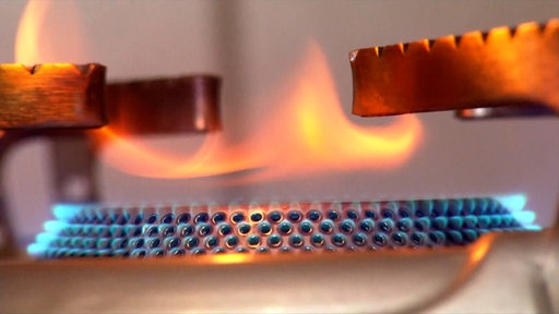 Auf dem Kochfeld eines Gasherdes brennt eine Flamme.