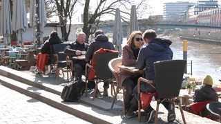 Restaurantbesucher sitzen an der Schlachte in Bremen.