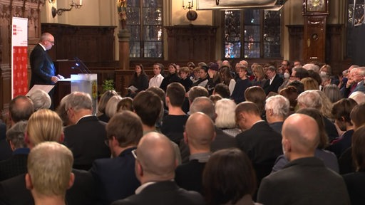 Viele Menschen hören Bürgermeister Bovenschulte bei einer Rede zum Gedenken an Opfer des Nationalsozialismus zu.