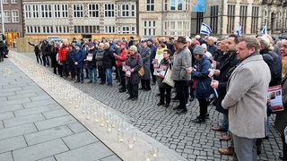 Menschen stehen vor der Bremischen Bürgerschaft. Auf den Stufen stehen viele Gläser mit Teelichtern.