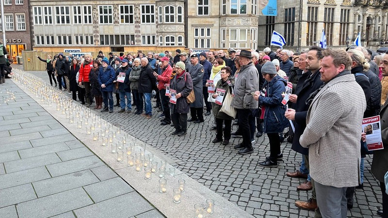Menschen stehen vor der Bremischen Bürgerschaft. Auf den Stufen stehen viele Gläser mit Teelichtern.