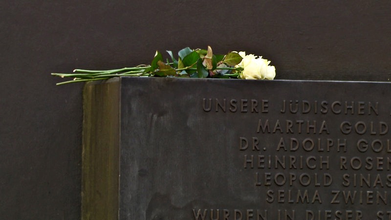 Der Gedenkstein der Rechspogromnacht in Bremen. Auf dem Gedenkstein liegen gelbe Rosen.