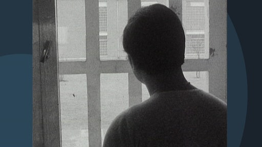 Ein Schwarz-/ Weißbild der Silhouette eines Gefängnisinsassen vor einem Fenster.