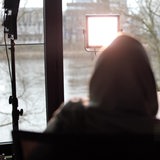 Eine Frau im Kapuzenpulli sitzt mit dem Rücken zur Kamera.