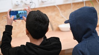 Zwei Jugendliche blicken auf ein Smartphone.