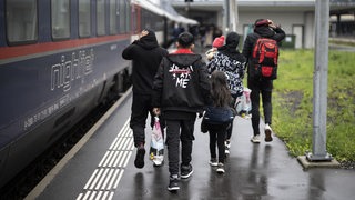 Eine geflüchtete afghanische Familie an einem Grenzbahnhof zu Deutschland. 