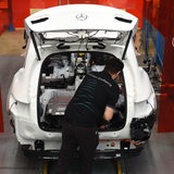 Ein Mitarbeiter von Mercedes-Benz in Bremen arbeitet an einem C-Klasse Hybrid Modell und bereitet den Einbau der Batterie vor.