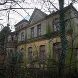Ein großes, verlassenes Haus steht hinter Bäumen