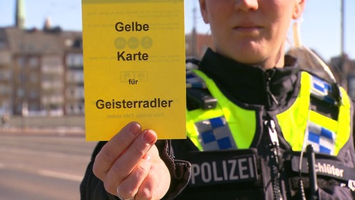 Eine Bremer Polizisten zeigt eine symbolische "gelbe Karte" für falsche Fahrradfahren