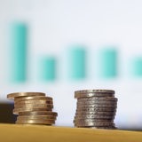 Euro-Münzen liegen aufgestapelt im Büro eines Steuerberaters vor einem Monitor