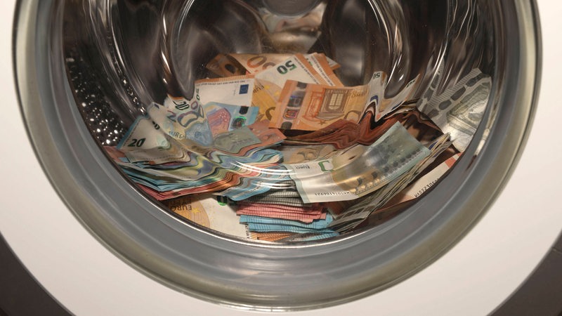 Geldschein in einer Waschtrommel als Symbol für Geldwäsche