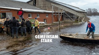 Landwirte transportieren Sandsäcke per Boot beim Hochwasser an der Wümme. Key-Visual: Gemeinsam Stark.