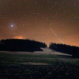 Geminiden-Sternschnuppen ziehen am Nachthimmel vorbei, Feld ist mit Schnee bedeckt