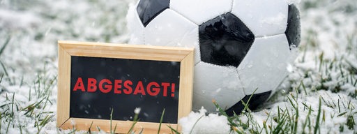 Im Schnee  liegt ein Fußball, davor in Schild mit der Aufschrift "Abgesagt"