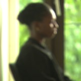 Eine unscharfe afrikanische Frau sitzt auf einem Stuhl vor einem Fenster