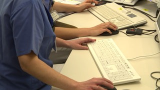 Zu sehen ist eine Angestellte eines Krankenhauses, die am Computer sitzt.