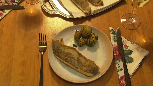 Ein Teller, auf dem ein Fischfilet und Kartoffeln angerichtet sind.