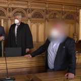 Drei Männer stehen in einem Bremer Gerichtssal. Einer von ihnen ist der geflohene Steuerhinterzieher Uwe Hirsch.