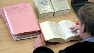 Richter vor Akten und Gesetzbüchern während einer Verhandlung (Symbolbild)
