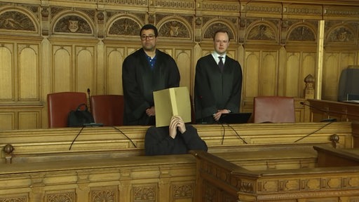 In dem Bremer Landgericht sitzt ein Angeklagter und hinter ihm stehen zwei Richter.