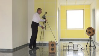 Der Aukustikingenieur Peter Gerlach steht mit seinen Geräten in einem leeren Raum um ihn auszumessen.