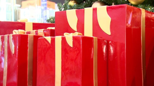 Geschenke vor einem Tannenbaum in einem Einkaufszentrum.