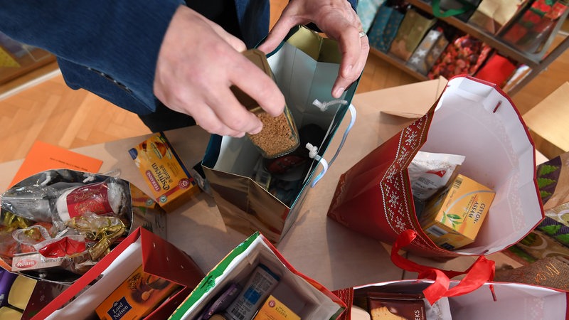 Ein Mann packt Spenden in eine Geschenktüte zu Weihnachten.