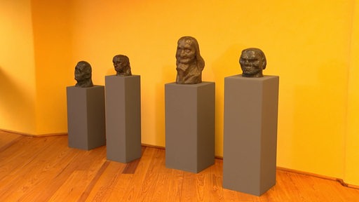 Eine Ausstellung die Gesichter auf einem Sockel zeigen.