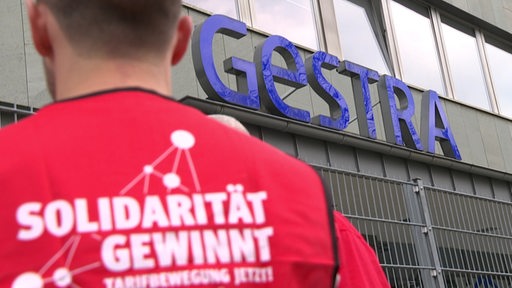 Ein Mann steht mit dem Rücken zur Kamera vor dem Gestra Gebäude.