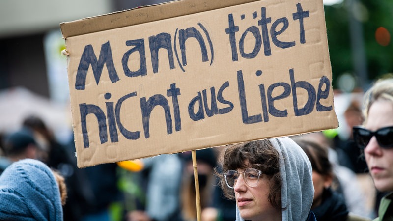 Bei einer Demonstration gegen Gewalt an Frauen hält eine Teilnehmerin ein Plakat mit der Aufschrift "Man(n) tötet nicht aus Liebe".