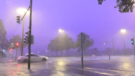 Ein Auto fährt bei starkem Regen und Gewitter über die bremer Domsheide-kreuzung.