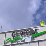 Auf einem grauen Gebäude hängt ein grünes Logo mit dem Schritzug "Gewoba". 