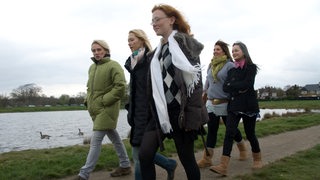 Eine Gruppe von Frauen spaziert an einem Fluss entlang.
