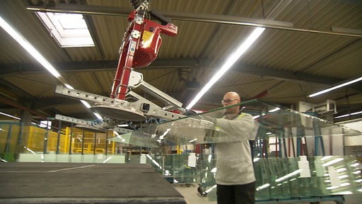 Ein Mitarbeiter arbeitet mit einer Maschine an einer Glasscheibe.
