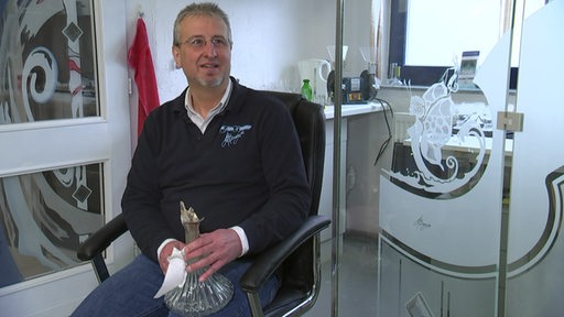 Der Glasdesigner Jens Barnerjee mit einer seiner Glasskulpturen in der Hand.
