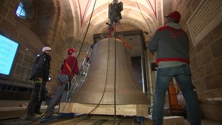 Zu sehen ist wie eine neue Glocke im Glockenturm des bremer Doms eingebaut wird.