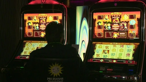 Ein Mann sitzt vor einem Glücksspielautomaten