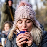 Eine Frau umklammert eine Glühwein-Tasse.