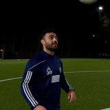 Ein Spieler im Trainingsanzug steht in der Dunkelheit auf einem Fußballplatz