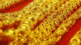 Goldschmuck liegt auf rotem Untergrund.