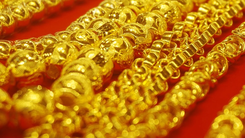 Goldschmuck liegt auf rotem Untergrund.